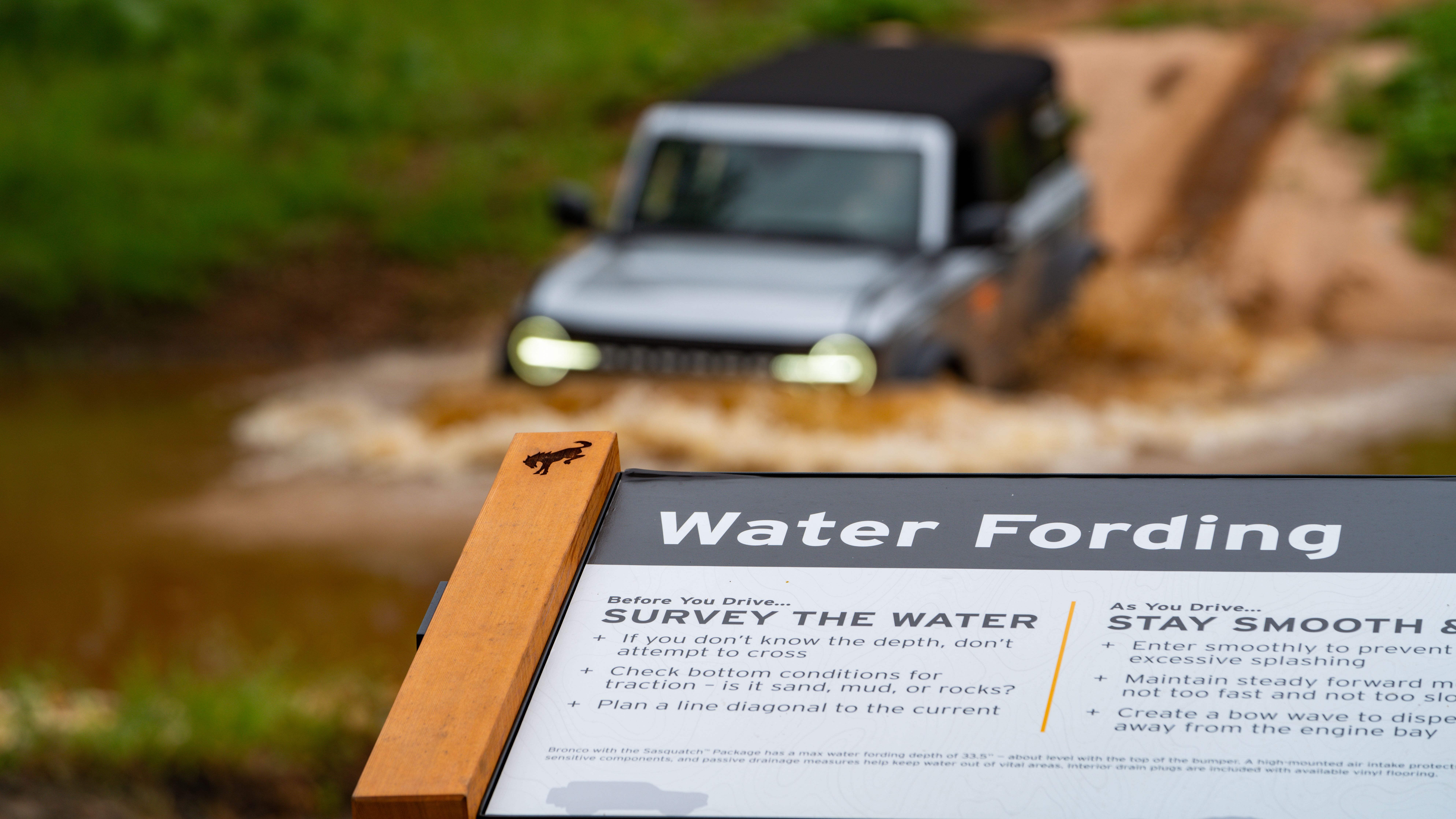 Bronco driving through water with instruction sign